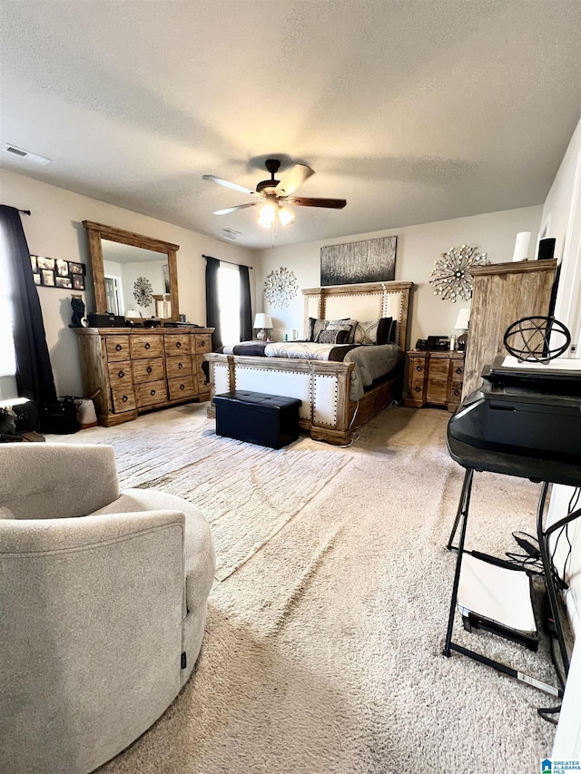 bedroom with ceiling fan, carpet floors, and a textured ceiling