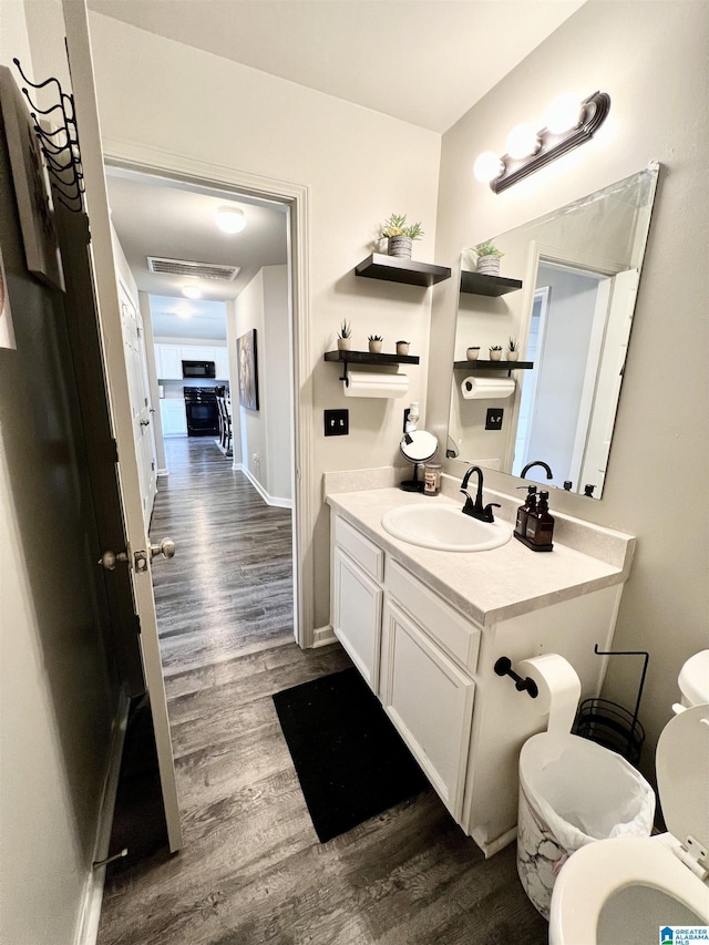 bathroom with wood-type flooring, vanity, and toilet