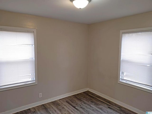 spare room with dark hardwood / wood-style flooring and plenty of natural light