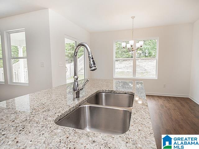 kitchen featuring light stone countertops, sink, hanging light fixtures, and plenty of natural light