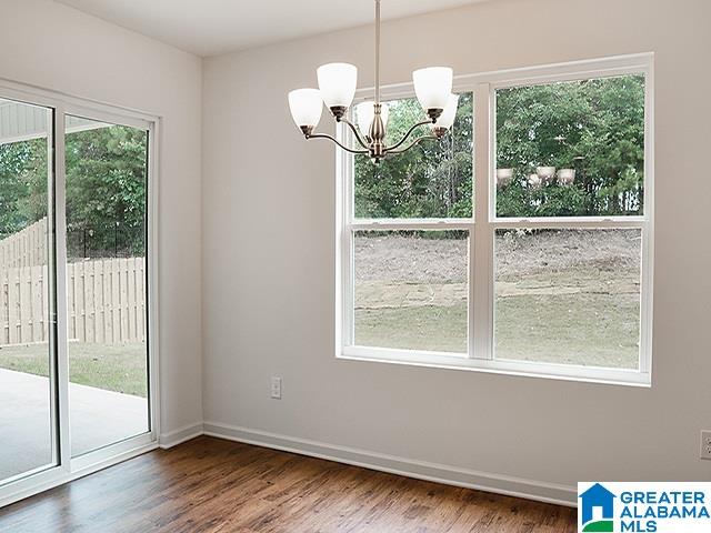 unfurnished dining area with dark hardwood / wood-style floors, a wealth of natural light, and a notable chandelier