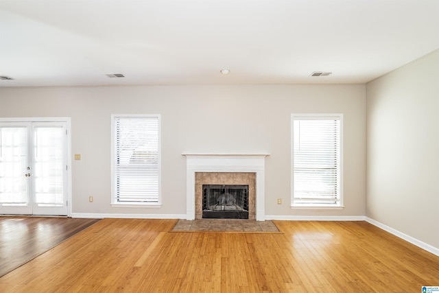 unfurnished living room featuring a tiled fireplace and light wood-type flooring