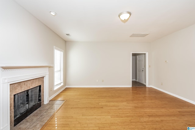 unfurnished living room featuring a tile fireplace and light wood-type flooring