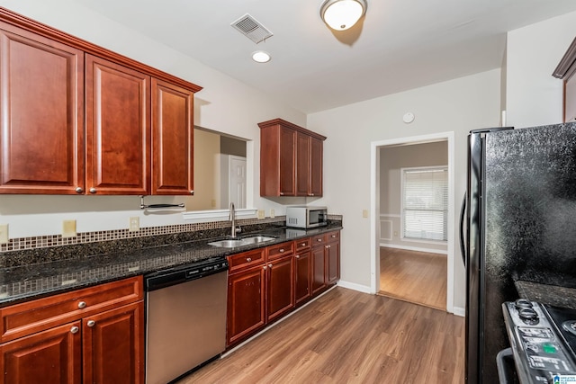 kitchen featuring dishwasher, white range, sink, hardwood / wood-style flooring, and dark stone countertops