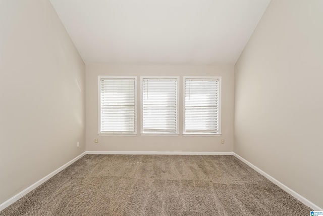 carpeted empty room with vaulted ceiling