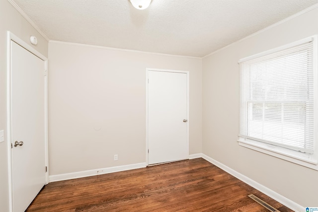 empty room featuring a textured ceiling, dark hardwood / wood-style flooring, and crown molding