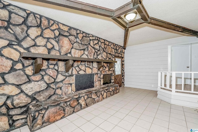 unfurnished living room with a stone fireplace, wooden walls, beamed ceiling, and light tile patterned floors