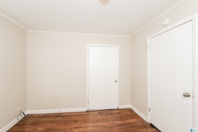 empty room with a textured ceiling, crown molding, and dark wood-type flooring