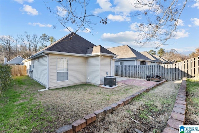 back of house with central AC unit and a lawn