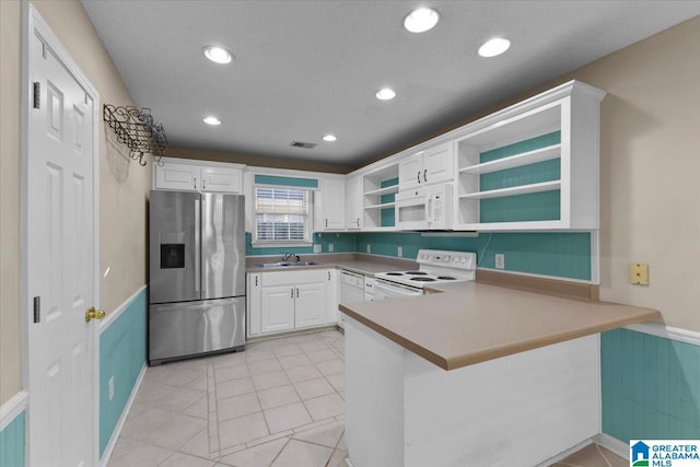 kitchen featuring white appliances, white cabinets, sink, light tile patterned floors, and kitchen peninsula