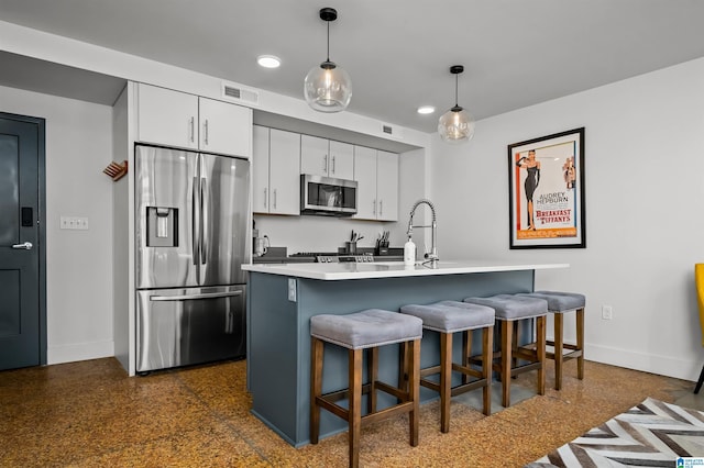 kitchen featuring a breakfast bar area, white cabinetry, decorative light fixtures, and appliances with stainless steel finishes