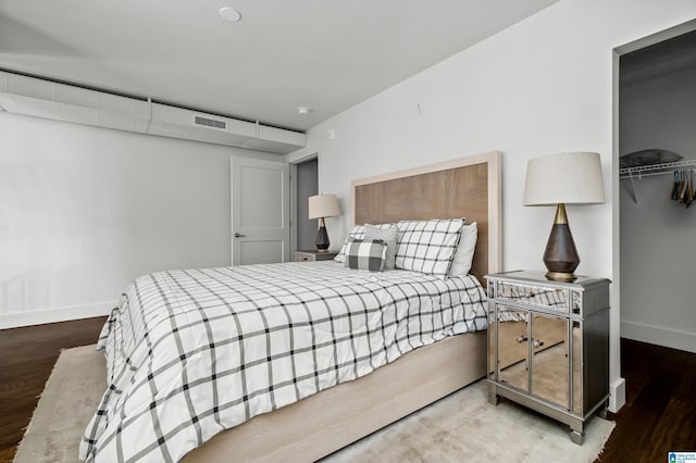 bedroom featuring a walk in closet, hardwood / wood-style flooring, and a closet