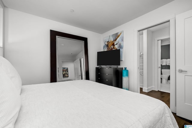 bedroom with dark wood-type flooring, connected bathroom, and a closet