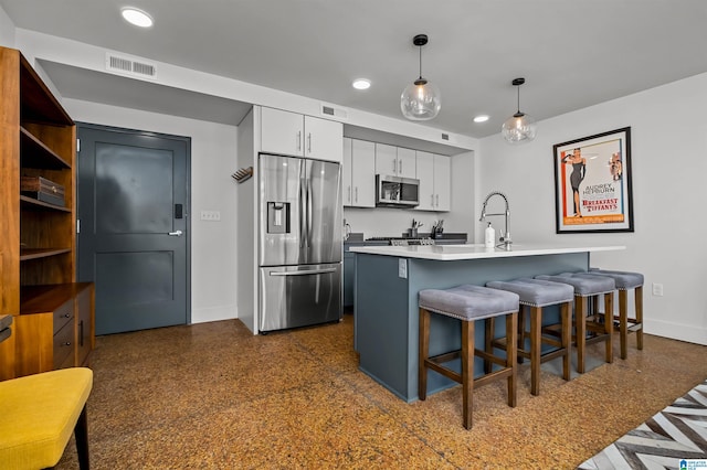 kitchen featuring white cabinets, a kitchen breakfast bar, sink, appliances with stainless steel finishes, and decorative light fixtures