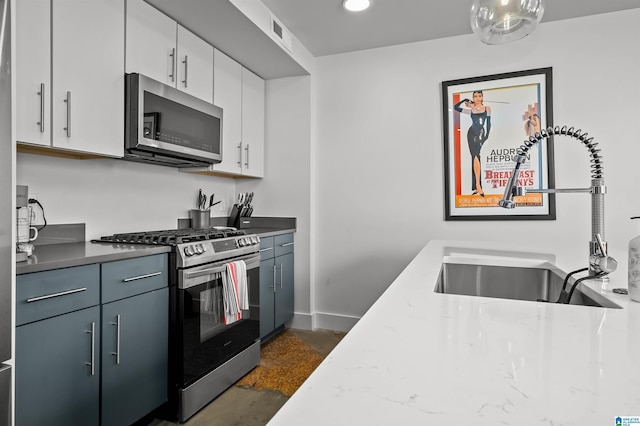 kitchen featuring light stone counters, stainless steel appliances, white cabinetry, and sink