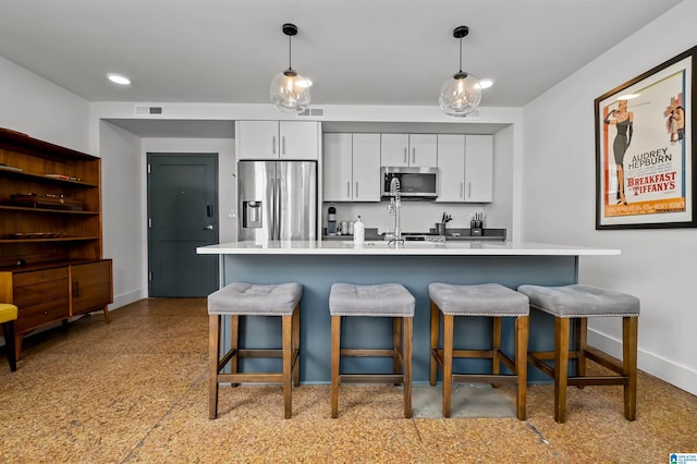 kitchen with decorative light fixtures, white cabinetry, a breakfast bar area, and appliances with stainless steel finishes