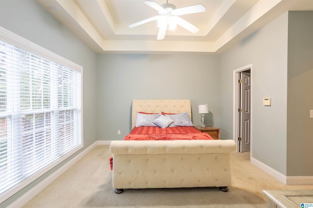 carpeted bedroom featuring a tray ceiling and ceiling fan