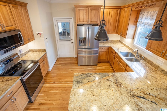 kitchen featuring light stone countertops, sink, stainless steel appliances, decorative light fixtures, and ornamental molding