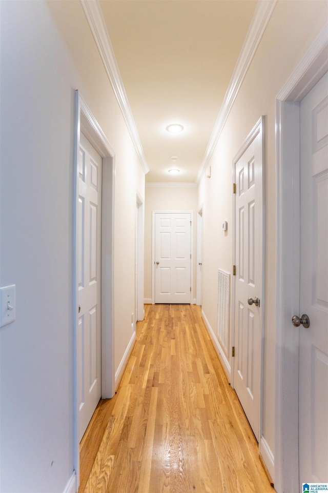 corridor with light hardwood / wood-style flooring and ornamental molding