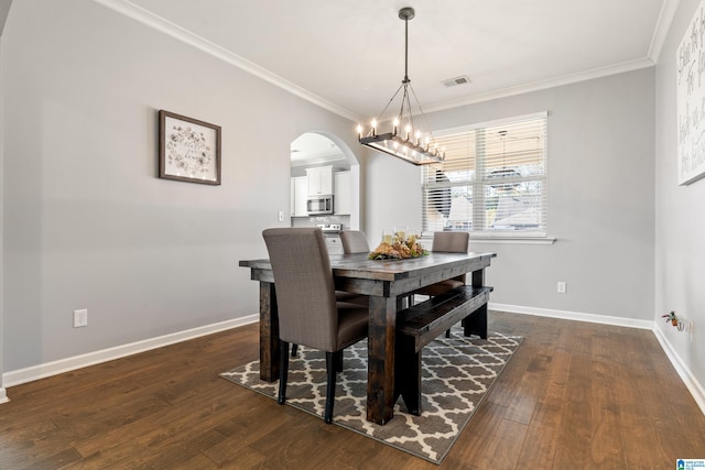 dining area featuring dark hardwood / wood-style floors, ornamental molding, and an inviting chandelier