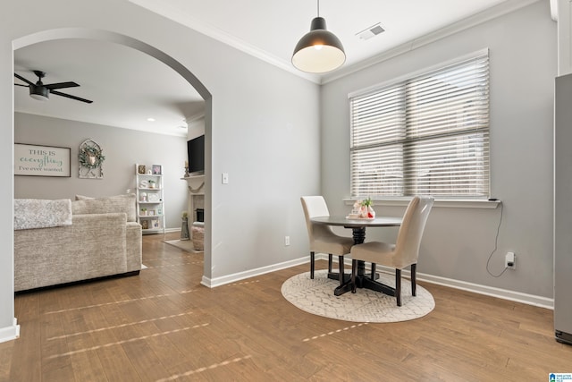 dining room with hardwood / wood-style flooring, ceiling fan, and crown molding