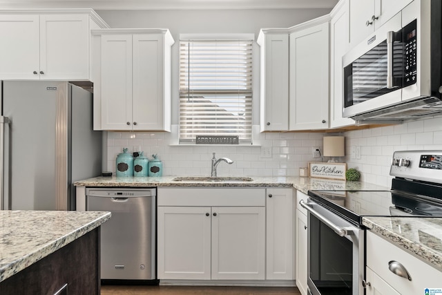 kitchen with backsplash, sink, white cabinets, and appliances with stainless steel finishes