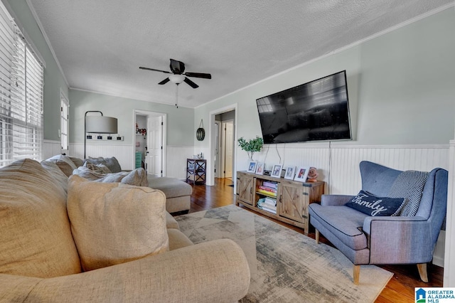 living room with wood-type flooring, a textured ceiling, ceiling fan, and crown molding