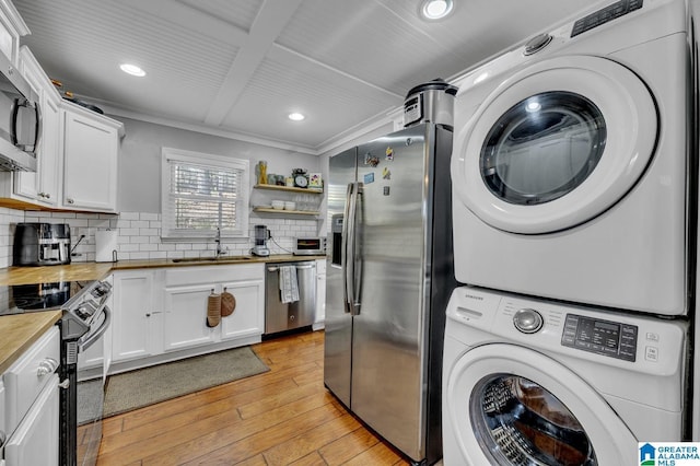 laundry room with sink, ornamental molding, stacked washer / drying machine, and light hardwood / wood-style flooring