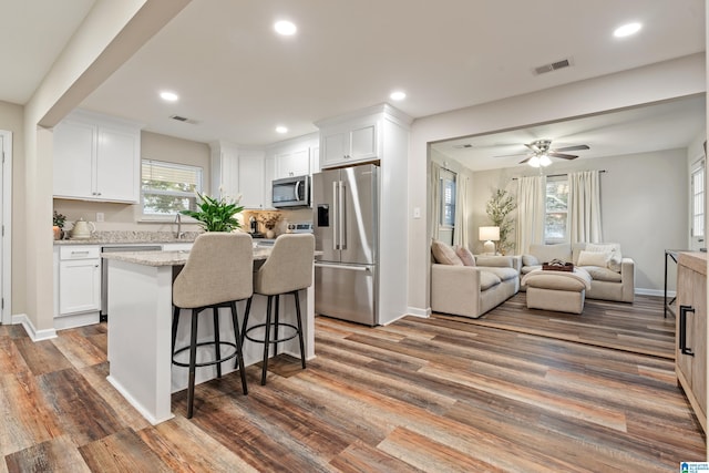 kitchen featuring light stone countertops, appliances with stainless steel finishes, white cabinetry, and dark wood-type flooring