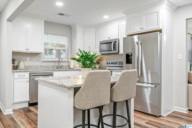 kitchen featuring white cabinets, a kitchen island, wood-type flooring, and appliances with stainless steel finishes