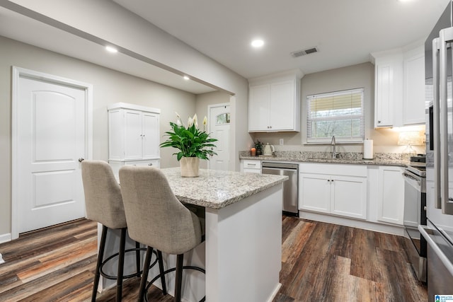 kitchen featuring appliances with stainless steel finishes, a center island, white cabinetry, and dark wood-type flooring