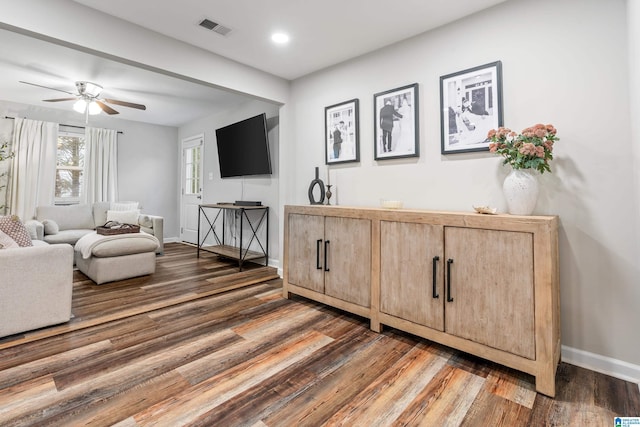 living room featuring ceiling fan and dark hardwood / wood-style flooring