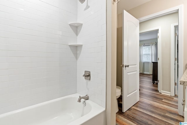 bathroom with hardwood / wood-style floors, tiled shower / bath combo, and toilet