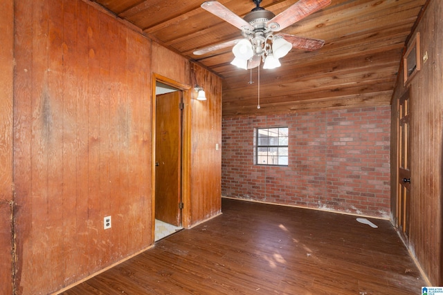 spare room featuring wooden ceiling, ceiling fan, brick wall, and dark hardwood / wood-style floors