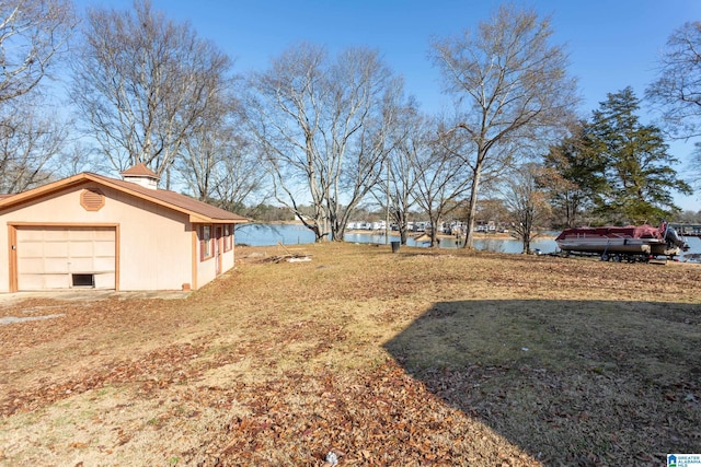 view of yard featuring a water view, a garage, and an outdoor structure