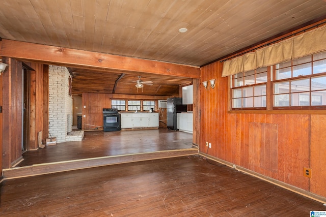 unfurnished living room featuring a wood stove, ceiling fan, wooden ceiling, dark hardwood / wood-style flooring, and wooden walls