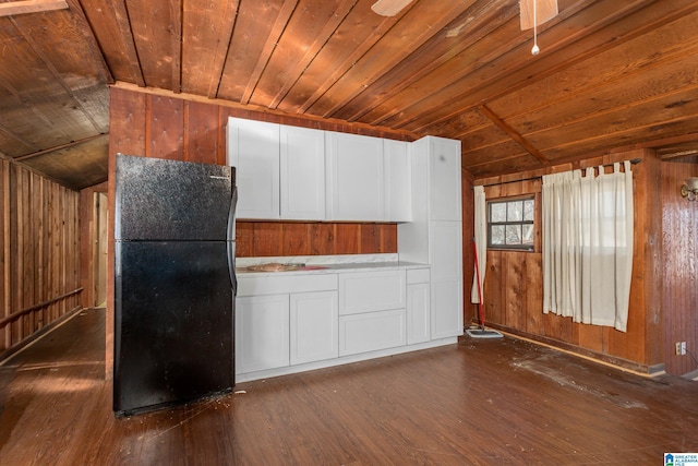 kitchen featuring wood walls, black refrigerator, dark hardwood / wood-style flooring, and wooden ceiling