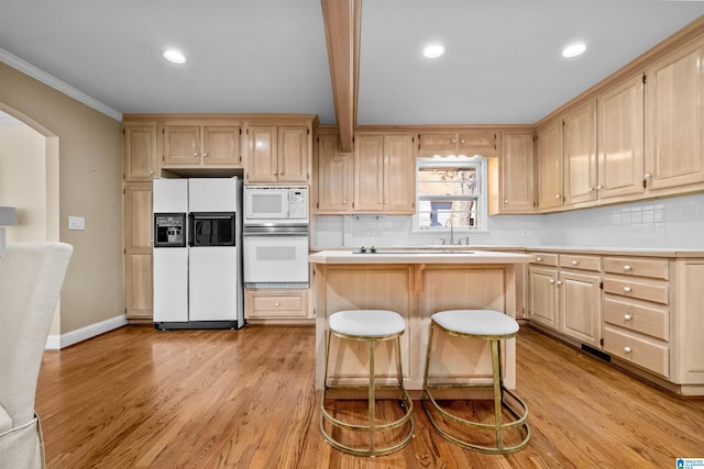 kitchen featuring a breakfast bar, a center island, white appliances, tasteful backsplash, and light hardwood / wood-style floors