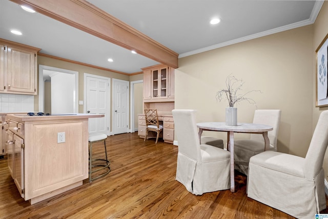 dining room with light wood-type flooring and crown molding