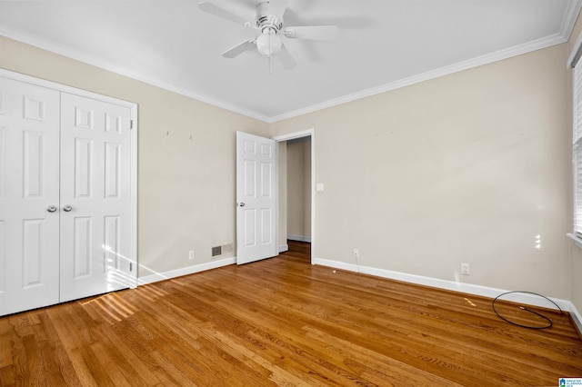 unfurnished bedroom featuring hardwood / wood-style floors, a closet, ceiling fan, and crown molding