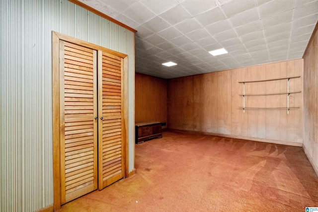 basement with a paneled ceiling and light colored carpet