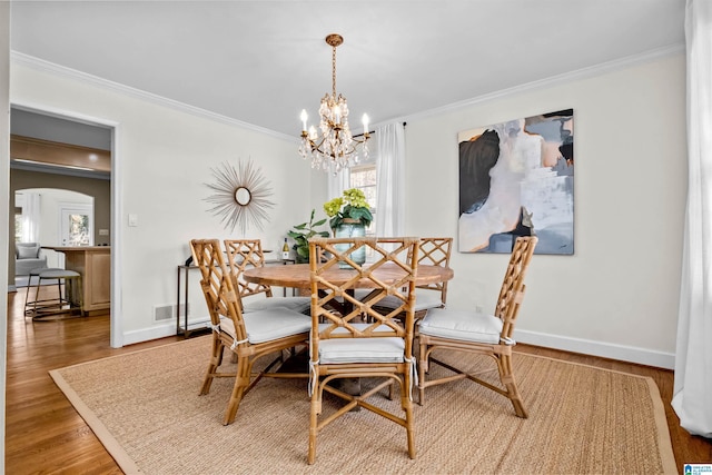 dining room featuring hardwood / wood-style floors, ornamental molding, and a notable chandelier