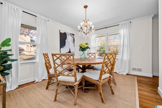 dining area with hardwood / wood-style flooring, an inviting chandelier, and ornamental molding