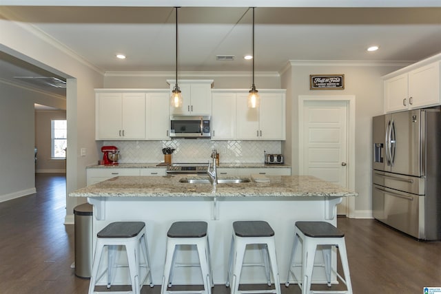 kitchen featuring a kitchen island with sink, white cabinets, pendant lighting, and appliances with stainless steel finishes