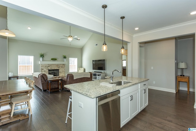 kitchen with light stone countertops, white cabinetry, sink, stainless steel dishwasher, and a kitchen island with sink