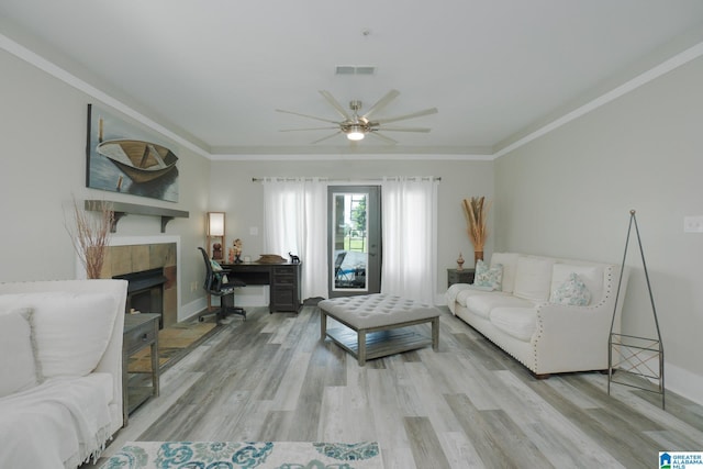 living room with a tile fireplace, ceiling fan, light hardwood / wood-style flooring, and ornamental molding