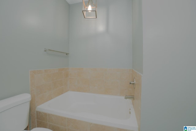 bathroom with toilet and tiled tub