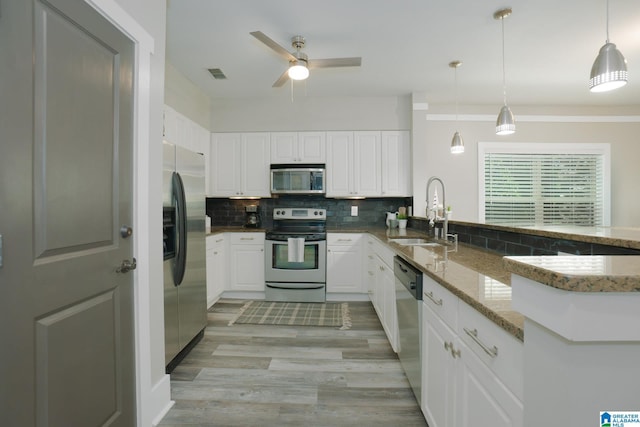 kitchen featuring sink, decorative light fixtures, light stone counters, white cabinetry, and stainless steel appliances