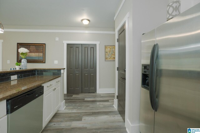 kitchen with white cabinets, light hardwood / wood-style flooring, appliances with stainless steel finishes, and dark stone counters