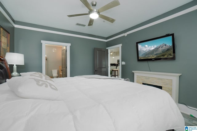 bedroom with ceiling fan, ornamental molding, ensuite bathroom, a fireplace, and hardwood / wood-style flooring